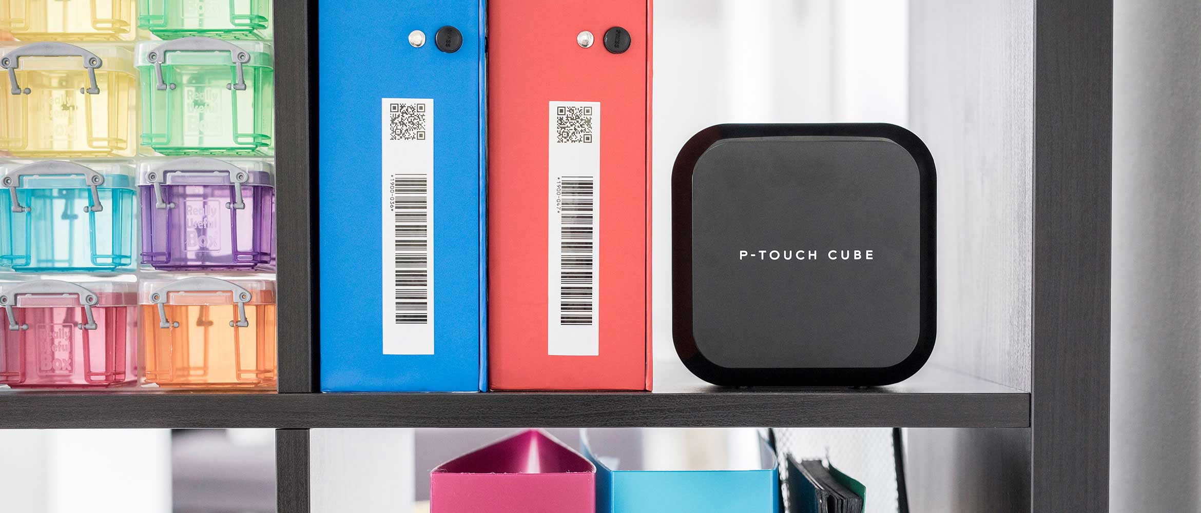 Brother P-touch labelprinter op een plank naast gelabelde dossiermappen met barcodes