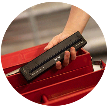 Person holding Brother PJ-7 compact printer in front of a red metal box
