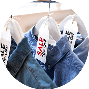 Red and black sale labels on hangers holding denim shirts