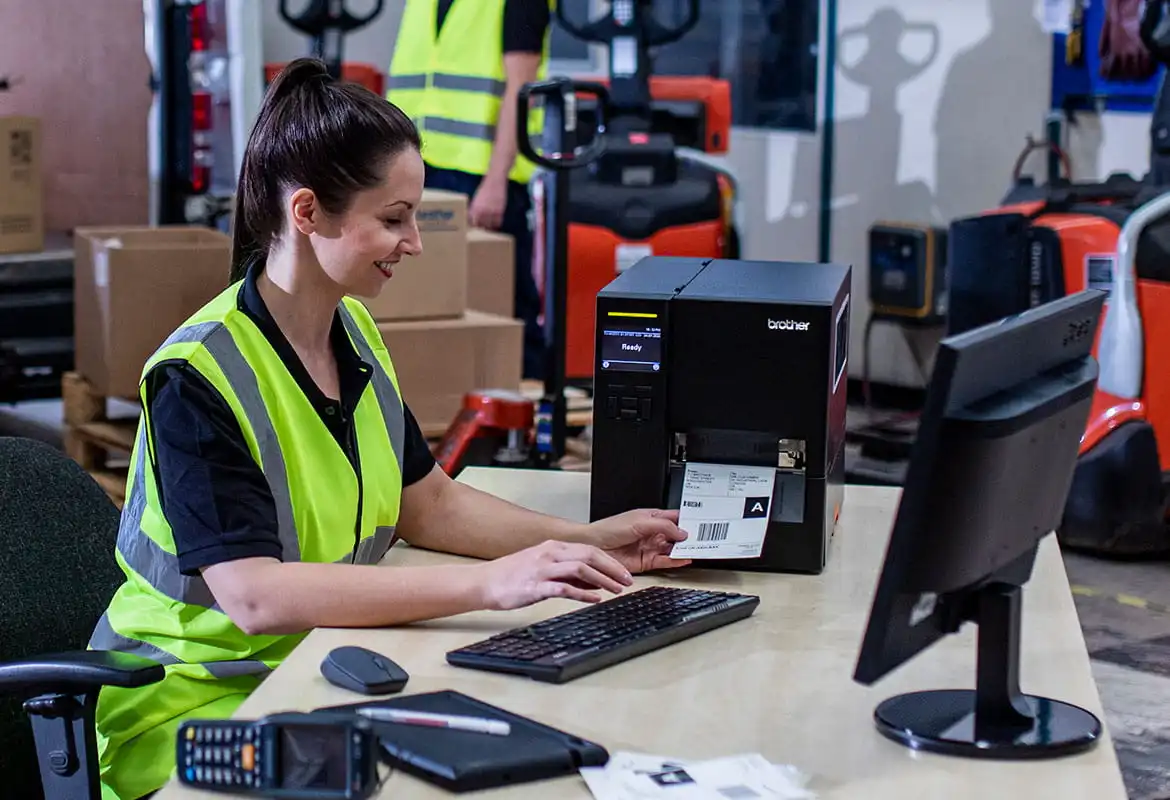 Warehouse arbeider met vest print bij bureau met industriële labelprinter van Brother