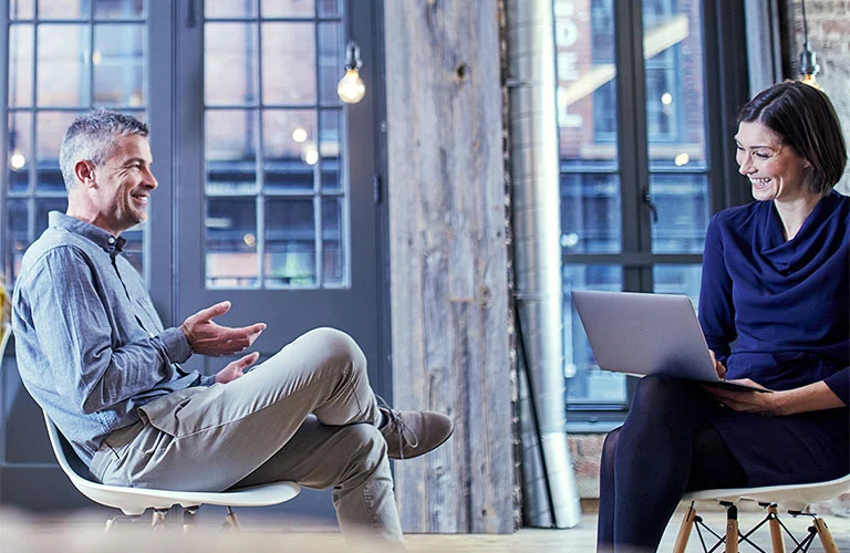 A man and a woman seated across from each other engaged in conversation
