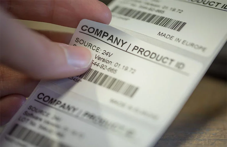 Close-up of a person peeling a custom self-adhesive company product ID label from a roll