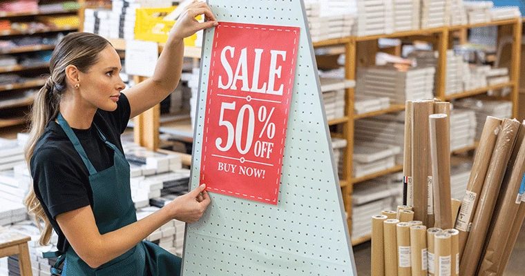 Female holding large format paper being put up in store