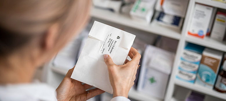 Medicijnetiket wordt op medicijnzakje in apotheek geplakt